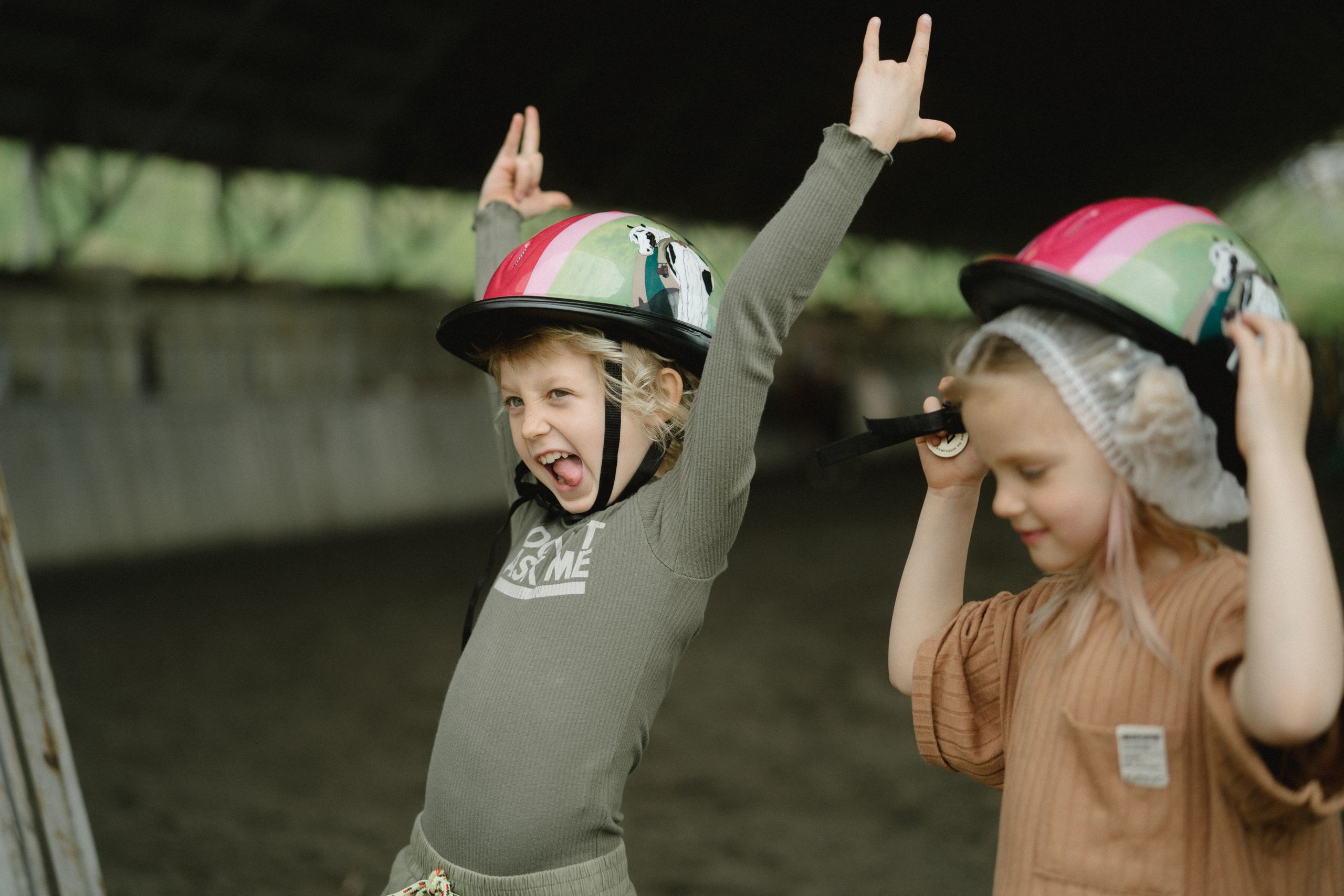 Two children enjoying playtime with colorful helmets, expressing joy and excitement indoors.
